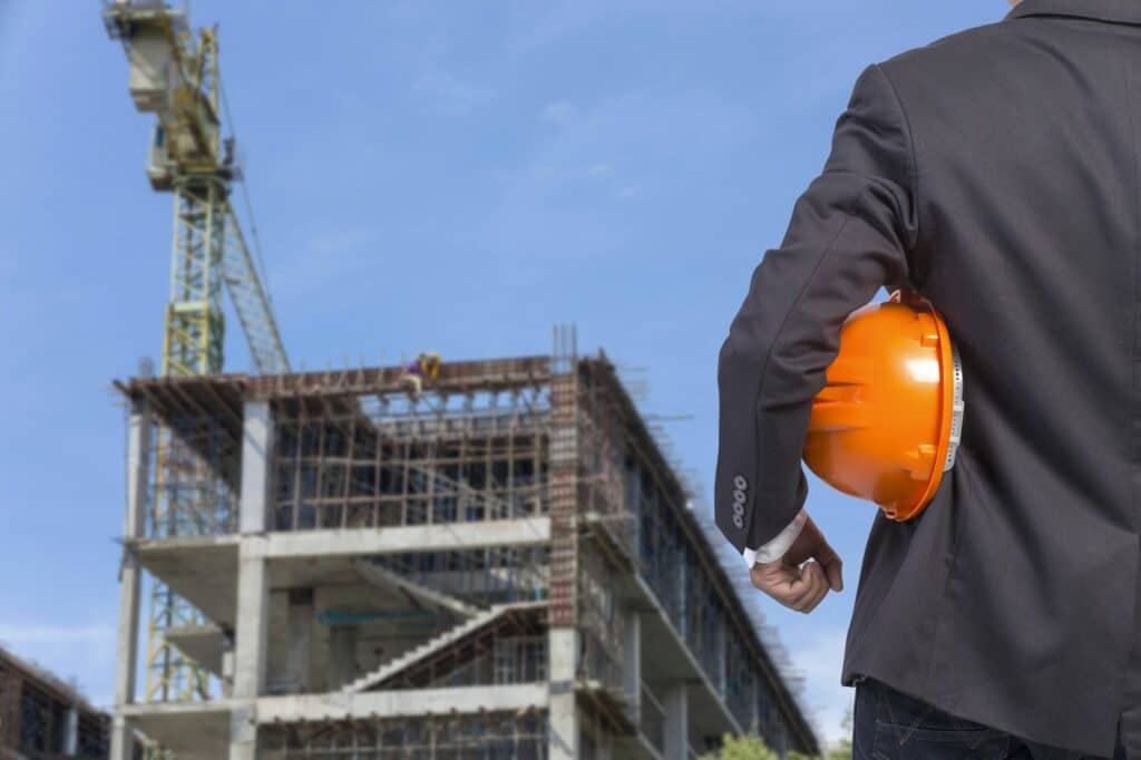 engineer holding orange helmet for workers security on contruction background